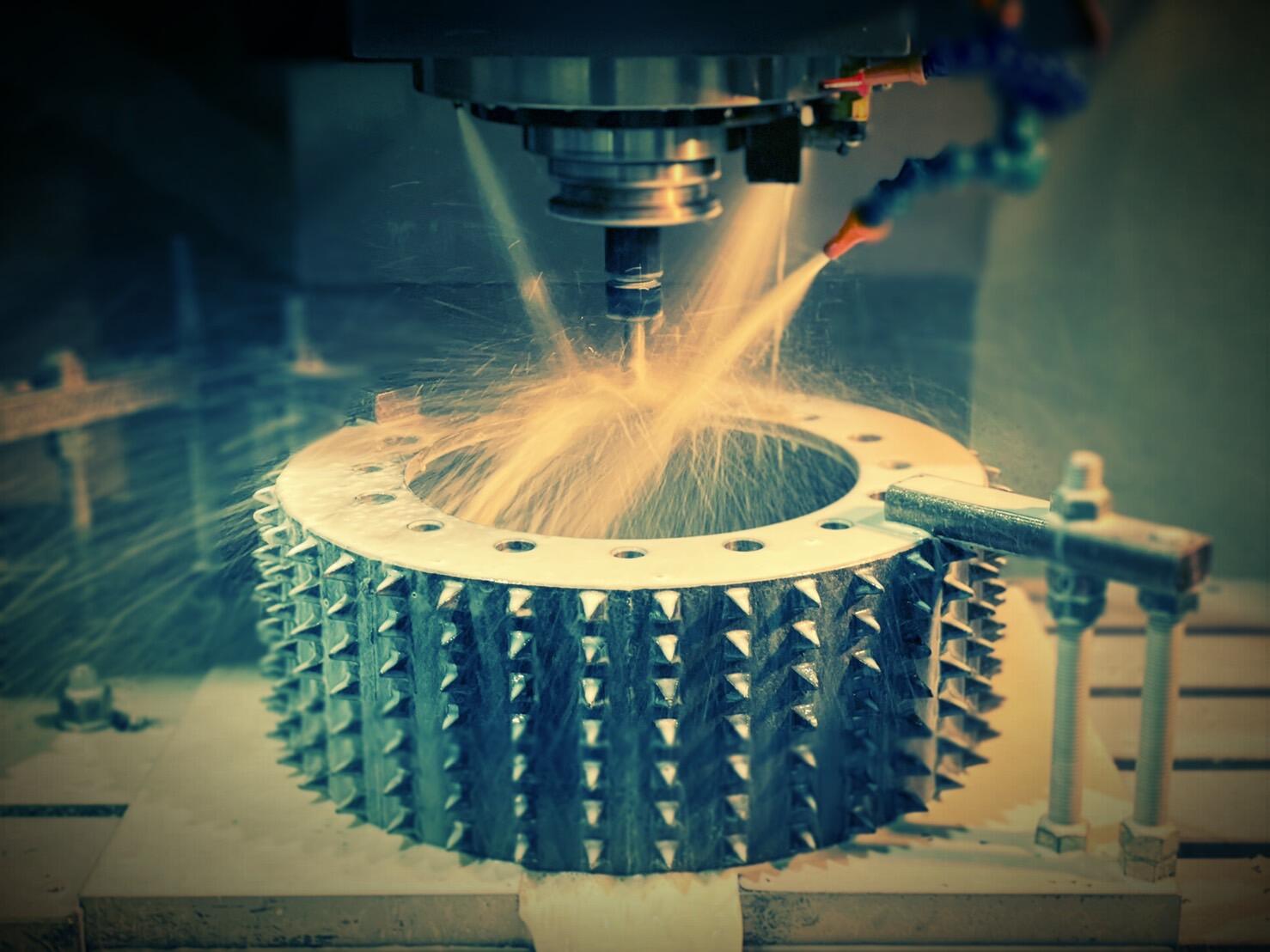 A close-up shot of a CNC machine milling a large, circular metal workpiece with a spiky, gear-like texture on its outer edge.